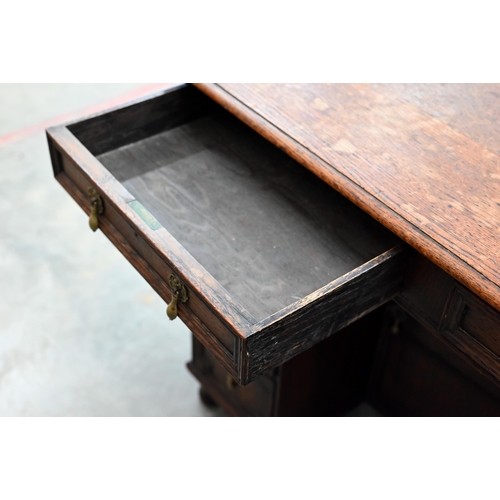 141 - A 19th century Jacobean style oak kneehole desk with eight drawers around the central recessed cupbo... 