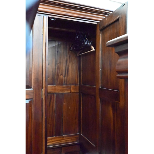 153 - A large modern stained hardwood triple wardrobe with panelled doors over six drawer base on low brac... 