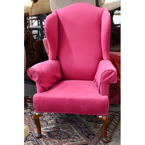 206 - An antique wingback armchair with bright pink fabric upholstery, on mahogany cabriole front legs