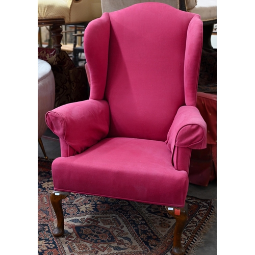 206 - An antique wingback armchair with bright pink fabric upholstery, on mahogany cabriole front legs