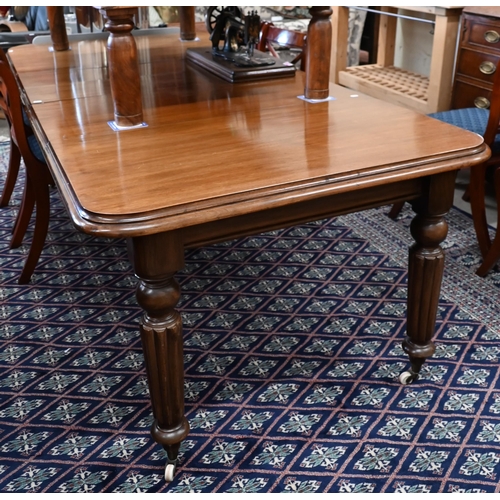 216 - A Victorian mahogany wind-out extending dining table with two leaves, raised on turned and fluted le... 