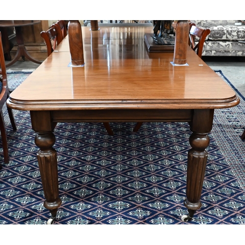 216 - A Victorian mahogany wind-out extending dining table with two leaves, raised on turned and fluted le... 