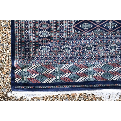 220 - A large Pakistani Turkoman design carpet, the blue ground with repeating gul design and multi-border... 