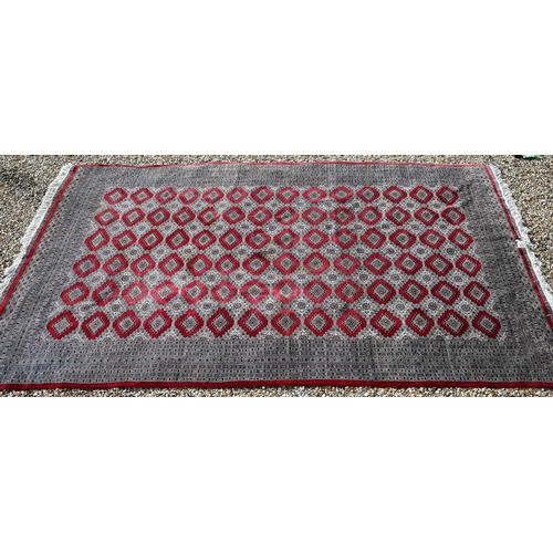 221 - A large Pakistani Turkoman design carpet, red ground with repeating gul design and multi-borders, 37... 