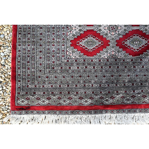 221 - A large Pakistani Turkoman design carpet, red ground with repeating gul design and multi-borders, 37... 