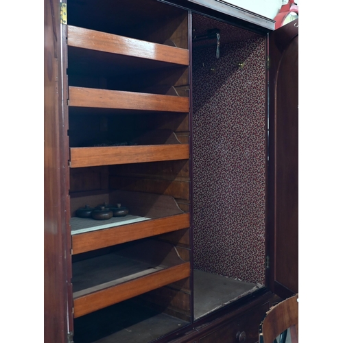 236 - A 19th century mahogany compactum wardrobe, arch panelled doors enclosing hanging space and slides o... 