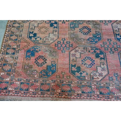 260 - A worn Afghan carpet, with rows of large octagonal guls on red ground, with geometric border, 320 x ... 