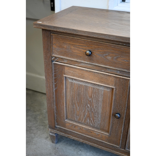 293 - A Multiyork limed oak sideboard with three drawers over panelled cupboards, on tapering square suppo... 