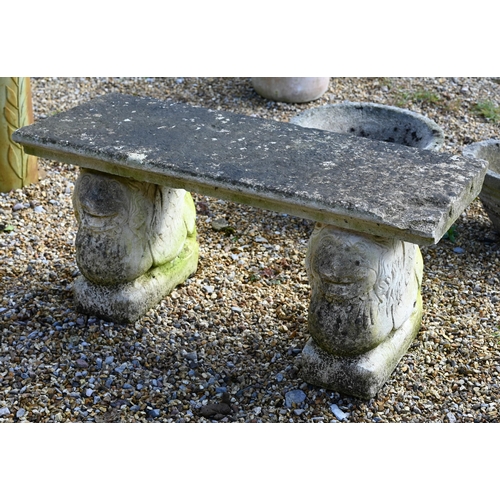 68 - A small weathered three piece cast stone garden bench, with lion form bases