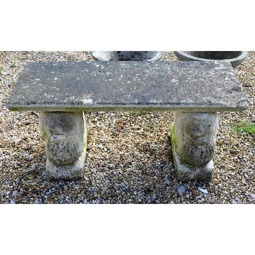 68 - A small weathered three piece cast stone garden bench, with lion form bases