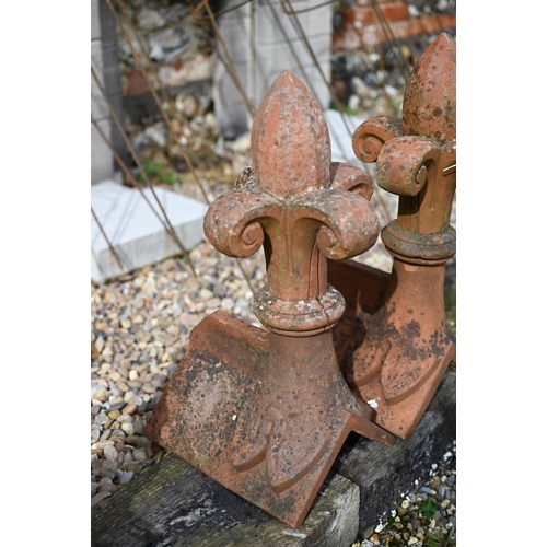 87 - A close pair of old weathered fleur-de-lys finial terracotta ridge tiles, a/f (2)