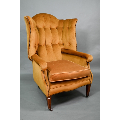 634 - An antique button and wing backed armchair raised on square tapering front legs to ceramic casters, ... 