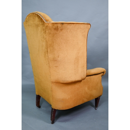 634 - An antique button and wing backed armchair raised on square tapering front legs to ceramic casters, ... 