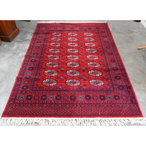 149 - A Turkoman design rug with repeat gul design on red ground 190 x 124 cm to/w similar machine made ex... 