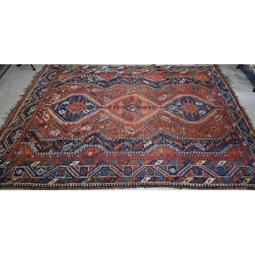 166 - A Persian Shiraz carpet with navy medallions on terracotta ground, 310 x 210 cm 