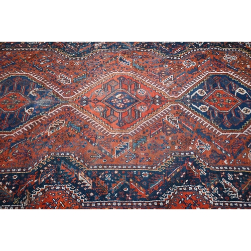 166 - A Persian Shiraz carpet with navy medallions on terracotta ground, 310 x 210 cm 