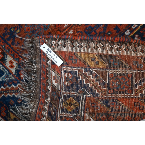 166 - A Persian Shiraz carpet with navy medallions on terracotta ground, 310 x 210 cm 