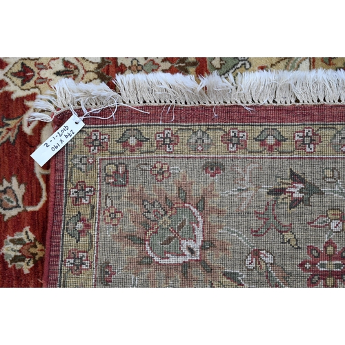 240 - An Indian Agra carpet, traditional floral design on terracotta field, beige rosette border, 274 cm x... 