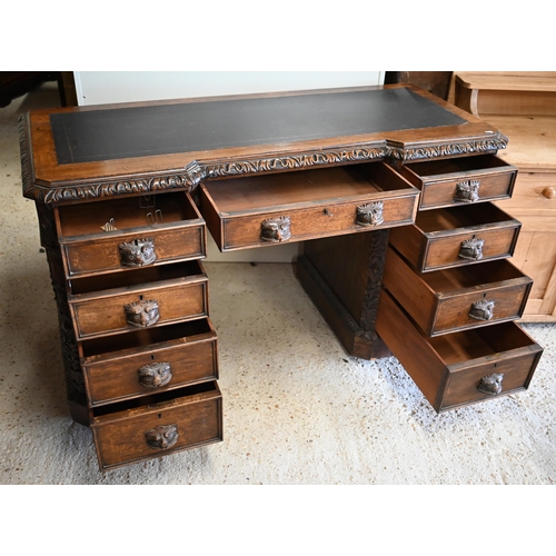 307 - A late Victorian Gothic Revival carved oak twin pedestal desk with nine drawers and 'Green Man' carv... 