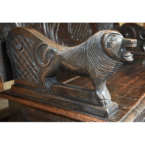 333 - A Gothic style oak monks' bench carved with armorial crest, foliate panels and roaring lion arms, 10... 