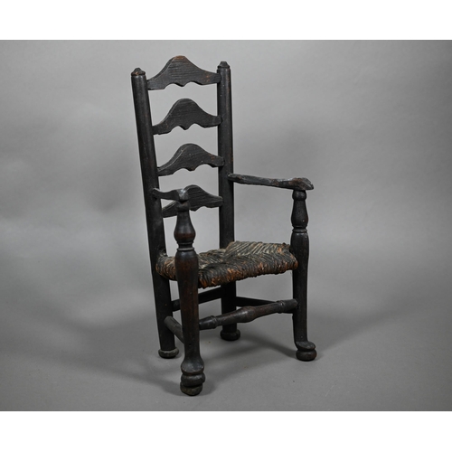 555 - An antique miniature ladderback armchair with rush seat, 35 cm