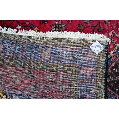 648 - A North West Persian runner, geometric medallions on red ground with navy borders 388 x 108cm