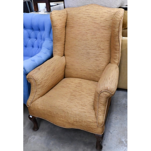 657 - #A wingback armchair covered in gold textured fabric, on cabriole supports