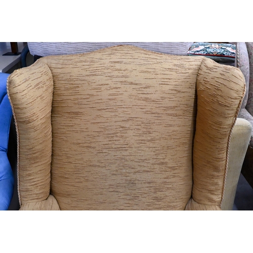 657 - #A wingback armchair covered in gold textured fabric, on cabriole supports