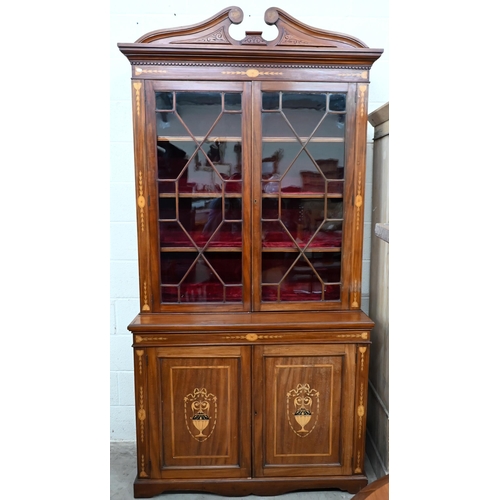 663 - An Edwardian inlaid mahogany cabinet bookcase with swan-neck moulded pediment above twin glazed door... 