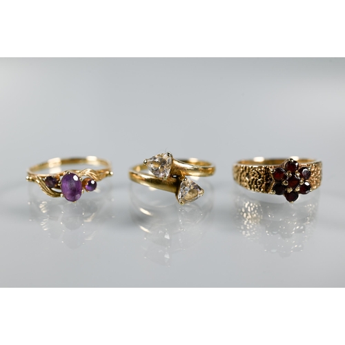 310 - Three 9ct yellow gold rings - a three-stone amethyst in scroll setting, garnet cluster and two stone... 