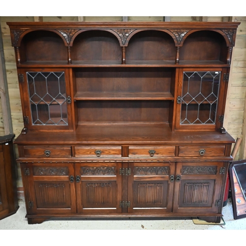 An Old Charm oak high dresser, with part lead glazed doors over four drawers and carved cupboards, raised on shaper bracket feet, 188 cm x 44 cm x 182 cm h