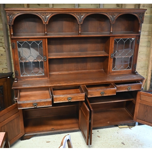 111 - An Old Charm oak high dresser, with part lead glazed doors over four drawers and carved cupboards, r... 