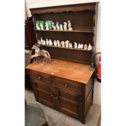 141 - An Old Charm style carved oak dresser with two drawers over panelled cupboard doors, 108 x 48 x 172 ... 