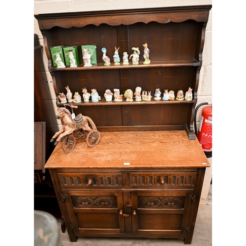 141 - An Old Charm style carved oak dresser with two drawers over panelled cupboard doors, 108 x 48 x 172 ... 