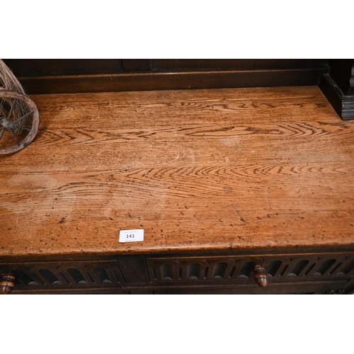 141 - An Old Charm style carved oak dresser with two drawers over panelled cupboard doors, 108 x 48 x 172 ... 