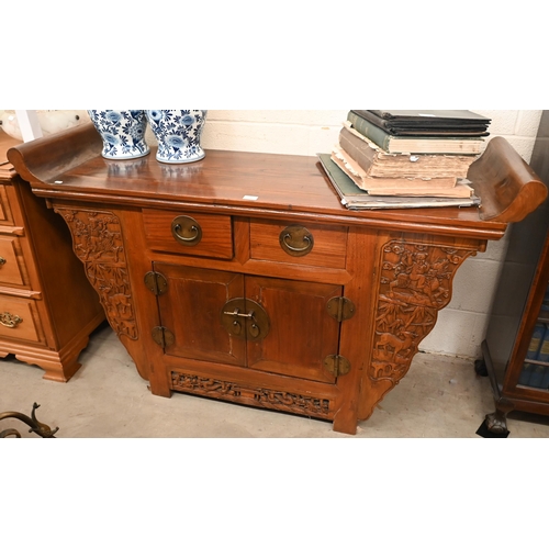 151 - A Chinese elm and brass mounted altar-top cabinet with two drawers and cupboards, decoratively carve... 