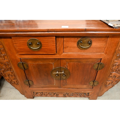 151 - A Chinese elm and brass mounted altar-top cabinet with two drawers and cupboards, decoratively carve... 