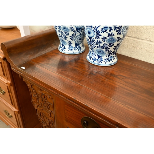 151 - A Chinese elm and brass mounted altar-top cabinet with two drawers and cupboards, decoratively carve... 