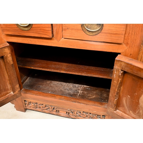 151 - A Chinese elm and brass mounted altar-top cabinet with two drawers and cupboards, decoratively carve... 