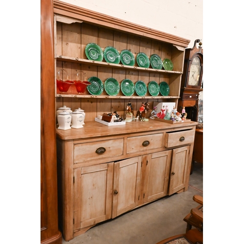 161 - A large Victorian stripped pine dresser with plate rack over three drawers and panelled cupboards (a... 