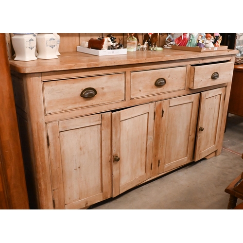 161 - A large Victorian stripped pine dresser with plate rack over three drawers and panelled cupboards (a... 