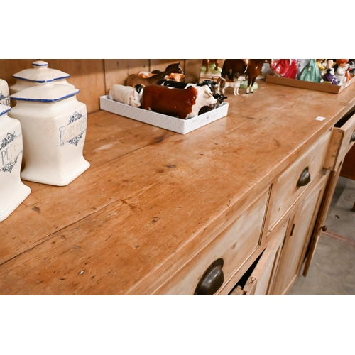 161 - A large Victorian stripped pine dresser with plate rack over three drawers and panelled cupboards (a... 