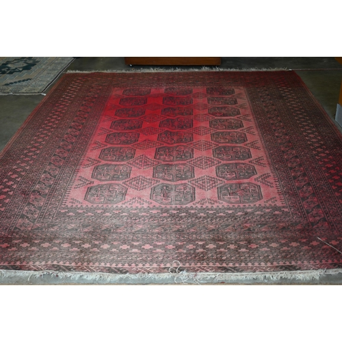 191 - An Afghan red ground carpet, repeating gul design and repeating borders