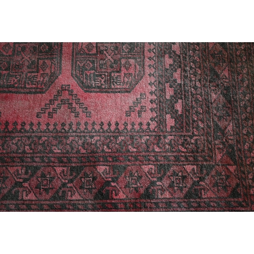 191 - An Afghan red ground carpet, repeating gul design and repeating borders