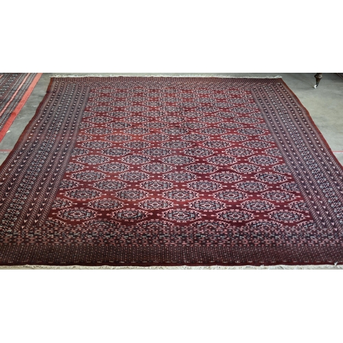 202 - A Pakistani Turkoman design wine ground carpet with repeating gul design within multi border, 312 x ... 