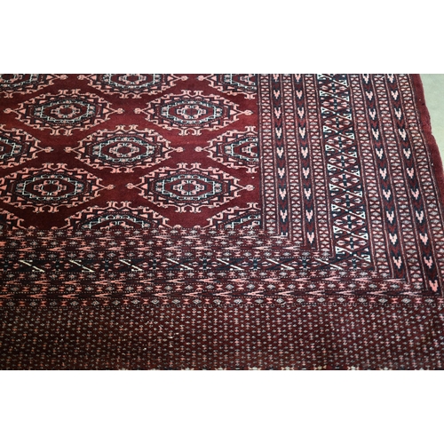 202 - A Pakistani Turkoman design wine ground carpet with repeating gul design within multi border, 312 x ... 