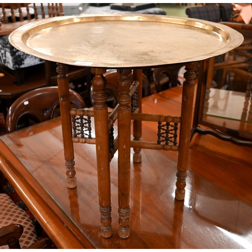 206 - A Middle Eastern engraved brass tray-top table on folding hardwood stand, 66 cm diam x 56 cm high