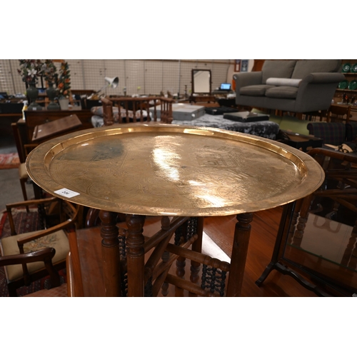 206 - A Middle Eastern engraved brass tray-top table on folding hardwood stand, 66 cm diam x 56 cm high