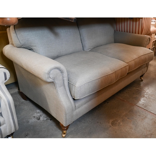 217 - Laura Ashley - a two-seater scroll arm sofa in stone linen-blend fabric on hardwood suports with bra... 