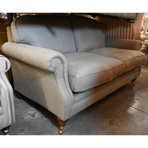 217 - Laura Ashley - a two-seater scroll arm sofa in stone linen-blend fabric on hardwood suports with bra... 